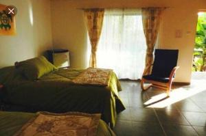 1 Schlafzimmer mit 2 Betten, einem Stuhl und einem Fenster in der Unterkunft Hostal Tu'u Koihu in Hanga Roa