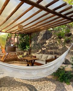 a hammock on a patio under a wooden pergola at Pousada Paraíso das Tartarugas in Pipa