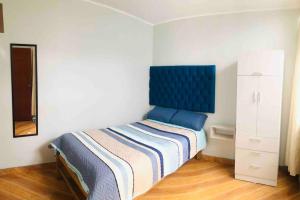 1 dormitorio con 1 cama con cabecero azul en Departamento moderno cerca del aeropuerto., en Lima