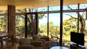 a living room with a large window with chairs and a television at Mt Singapore Villas - Villa 2 in Yanakie