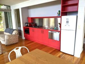 cocina con armarios rojos y nevera blanca en Mt Singapore Villas - Villa 2, en Yanakie