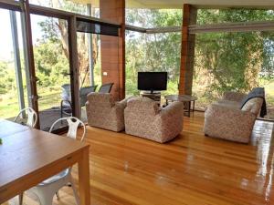 a living room with chairs and a television on a wooden floor at Mt Singapore Villas - Villa 2 in Yanakie