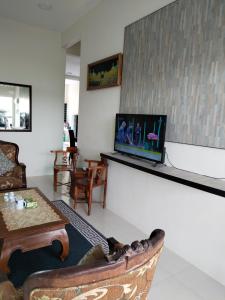 Lekir baiduri homestay في سيتياوان: غرفة معيشة مع أريكة وتلفزيون على الحائط