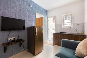 uma sala de estar com uma televisão e um frigorífico em StayhomeStays Prime em Bangalore