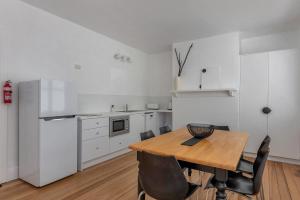 a white kitchen with a wooden table and chairs at Best on Letitia Central spacious stylish sleeps 6 in Hobart