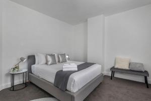 a white bedroom with a bed and a chair at Best on Letitia Central spacious stylish sleeps 6 in Hobart