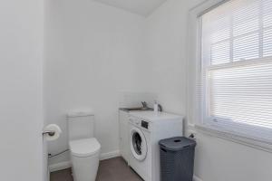 a white bathroom with a washing machine and a toilet at Best on Letitia Central spacious stylish sleeps 6 in Hobart