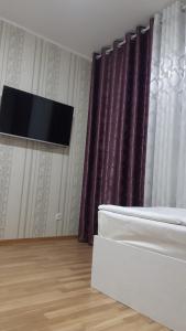 1 dormitorio con 1 cama y TV en la pared en Гостиничный дом Эко, en Karakol