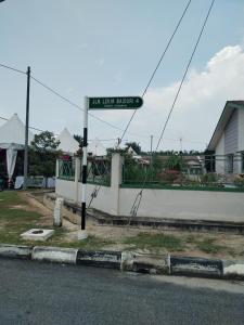 un letrero de calle en un poste al lado de una calle en Lekir baiduri homestay, en Sitiawan