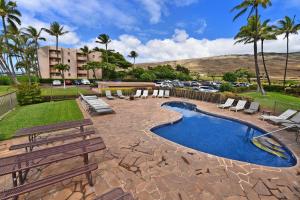 a patio with a pool and benches and a parking lot at Island Sands 210 in Maalaea