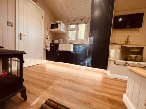 a kitchen with black cabinets and a wooden floor at Bodos’ Shepards Hut in Durham