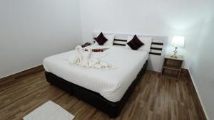 a bedroom with a large white bed with swans on it at Bouasavan Hotel and Garden in Savannakhet