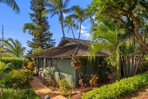 une maison verte avec des palmiers devant elle dans l'établissement International Colony Club 13, à Lahaina