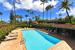 a swimming pool next to a resort with palm trees at International Colony Club 13 in Lahaina