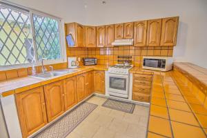 a kitchen with wooden cabinets and white appliances at Las Palmas Golden Zone Duplex - Pool & Sunset Rooftop in Bucerías