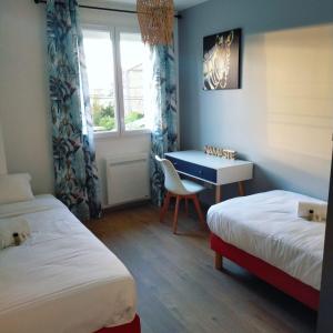 um quarto com 2 camas, uma secretária e uma janela em Gîte des Gônes - Lyon Charme em Feyzin