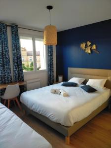 - une chambre avec un grand lit blanc et un mur bleu dans l'établissement Gîte des Gônes - Lyon Charme, à Feyzin