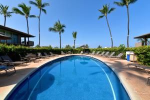 a large swimming pool with chairs and palm trees at Eldorado K104 in Kahana