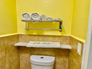 Baño con aseo y toallas en una pared amarilla en 4 Star Motel, en Los Ángeles