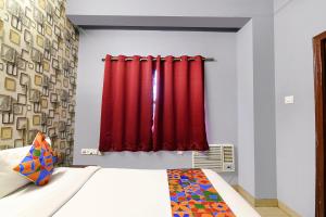 a bedroom with a bed with red curtains at FabExpress Westin Palaza in kolkata