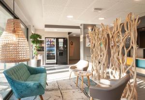 a lobby with chairs and a couch and trees at B&B HOTEL Pau Zénith in Pau