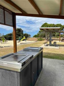 an outdoor grill with a playground in the background at Sea Rest in Forster