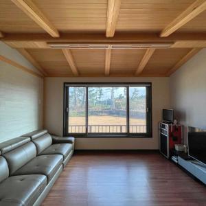 a living room with a couch and a large window at Jeju Sunshine Pension in Jeju