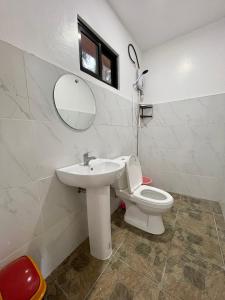 W łazience znajduje się umywalka, toaleta i lustro. w obiekcie Ana's Bungalow w mieście Siquijor