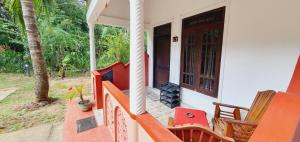 um alpendre de uma casa com cadeiras e uma porta em SMW Lodge Sigiriya em Sigiriya