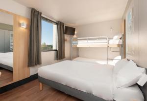 um quarto de hotel com uma cama e beliches em B&B HOTEL Pau Zénith em Pau