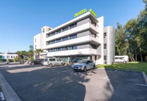 a hotel with cars parked in a parking lot at B&B HOTEL Pau Zénith in Pau