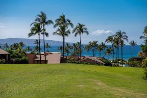 a lawn with palm trees and the ocean in the background at Wailea Ekahi 32B in Wailea