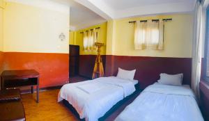 Cette chambre comprend deux lits, un bureau et un piano. dans l'établissement Thamel Hub Hostel, à Katmandou
