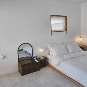Schlafzimmer mit einem weißen Bett und einem Spiegel in der Unterkunft Exclusive House Hanok Stay 'Soo Hanok' in Suncheon