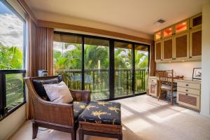 a living room with a chair and a desk and windows at Wailea Ekahi 17D in Wailea