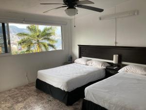 duas camas num quarto de hotel com uma janela em Casa Breizh em Acapulco