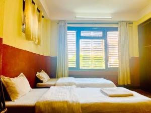 - une chambre avec 2 lits et une fenêtre avec des stores dans l'établissement Thamel Hub Hostel, à Katmandou