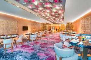 a dining room with tables and chairs on a pink rug at Meixi Lake Hotel, a Luxury Collection Hotel, Changsha in Changsha