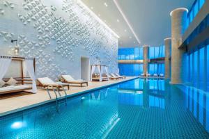 a pool in a hotel with chairs and a swimming pool at Meixi Lake Hotel, a Luxury Collection Hotel, Changsha in Changsha