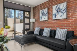 uma sala de estar com um sofá preto e uma parede de tijolos em Easy Stay - The Vantage Rosebank em Joanesburgo