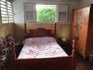 een slaapkamer met een houten bed met een witte en rode deken bij chez titine in Guenouillet
