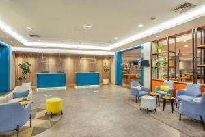 a lobby with blue and yellow chairs and tables at 1O1 URBAN Jakarta Kelapa Gading in Jakarta