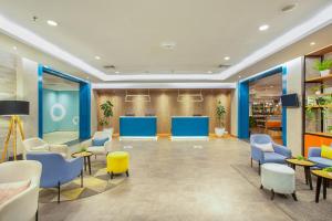 a waiting room with blue and yellow chairs and tables at 1O1 URBAN Jakarta Kelapa Gading in Jakarta