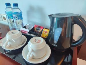 a counter top with a coffee pot and two cups at Kuta One Party Hotel in Kuta