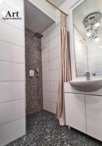 a white bathroom with a sink and a shower at Art Apartamenty Złota in Kalisz