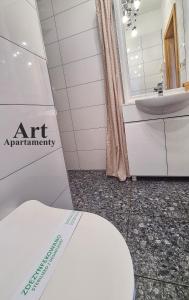 a white bathroom with a toilet and a sink at Art Apartamenty Złota in Kalisz