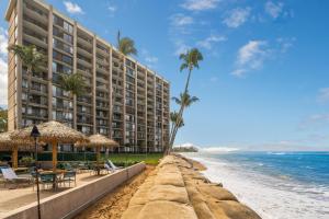 a hotel on the beach with palm trees and the ocean at Valley Isle 401 in Kahana