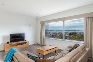 ein Wohnzimmer mit Couch und großem Fenster in der Unterkunft City Lights Spacious walk to restaurant strip in New Town