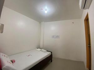 a small room with a bed and a light on the ceiling at WJV INN MARIBAG0 in Maribago