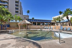 a swimming pool with a umbrella and chairs and a building at Sands of Kahana 354 in Kahana